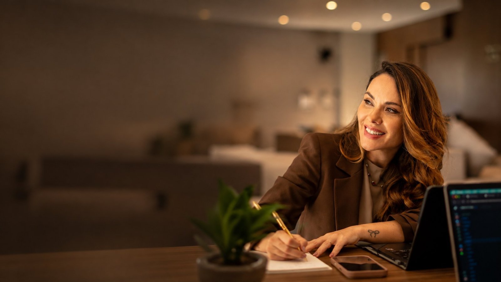 Valéria Carinhato sorrindo durante uma conversa, à mesa com caderno e notebook