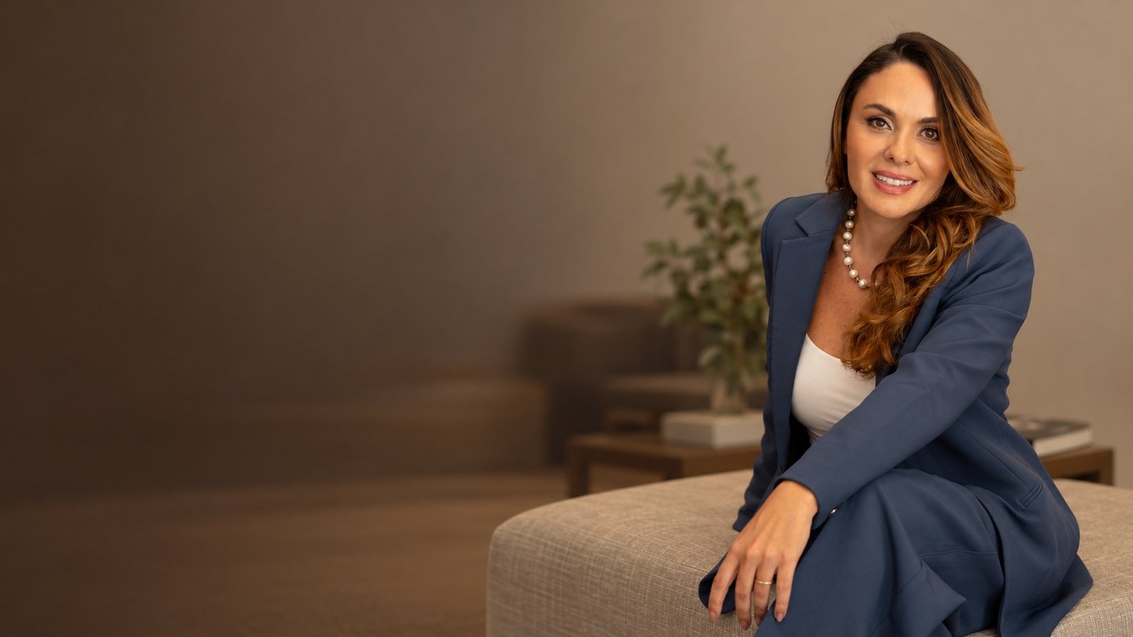 Valéria Carinhato de terno azul, sentada e sorrindo